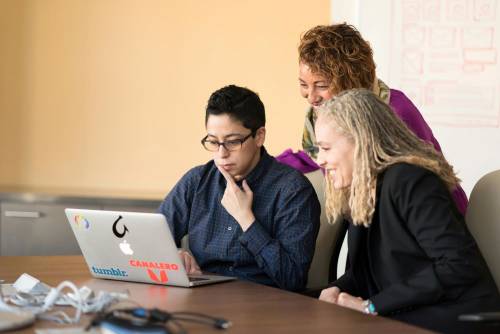 three people sitting at a table for a business meeting